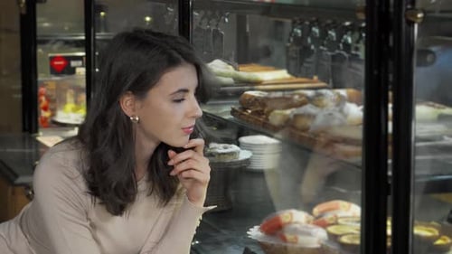 Charming Young Woman Beams at the Camera While Shopping at a Delightful Bakery