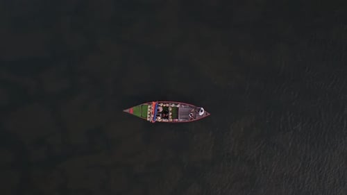 Un Drone suit un bateau naviguant sur une rivière calme