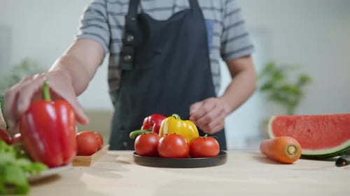 Healthy man preparing organic fruit and vegetable salad at home for healthy lifestyle