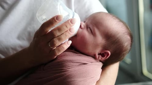 Loving Parent Feeds Newborn Baby with Bottle