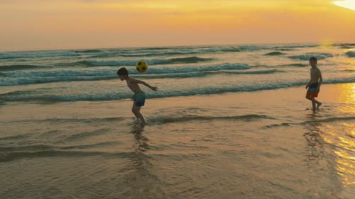 Children Playing Soccer on the Beach at Sunset