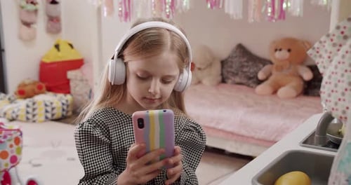 Girl with Headphones Watching Smartphone in Bedroom