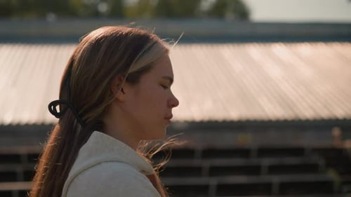 Reflective Woman Walking By Empty Stadium Bleachers in Thoughtful Mood