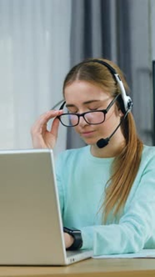 Tired Hardworking Beautiful 20Aged Girl in Casual Clothes in Headphones Taking Off Eyeglasses and