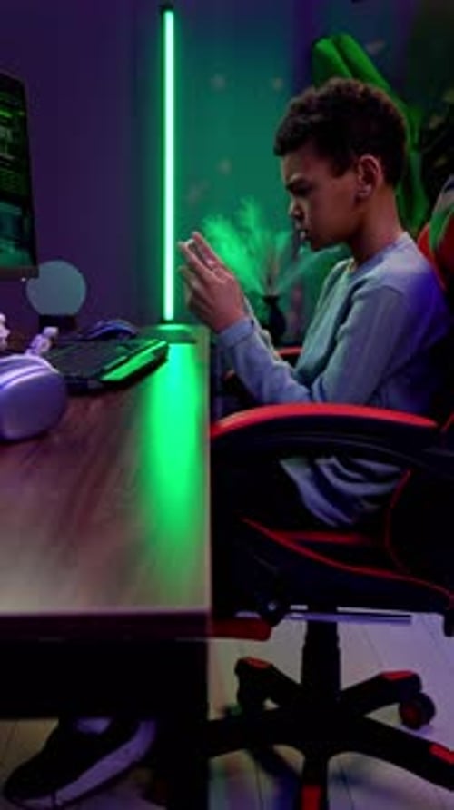 Teen Playing on Phone at Gaming Desk