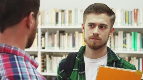 Students Talk in Library in Front of Bookshelf
