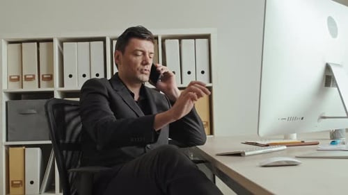 Attractive Businessman Talking on Mobile Phone in Office