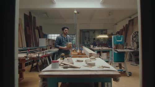Man Sanding Wood in Bright Workshop