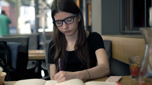 Teenage Girl with Smartphone Doing Homework Sitting in Cafe Alone