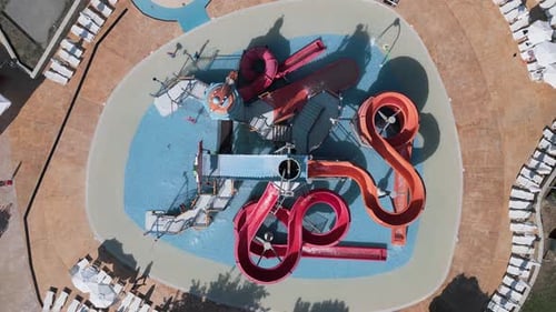 Aerial View of a Colorful Children's Water Playground with Twisting Slides Shallow Pool and Kids