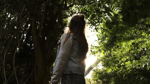 Junge Frau blickt auf Sonnenschein, Wald, Baumkronen, Freiheit, Unabhängigkeitskonzept, Zeitlupe