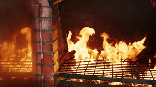 Nahaufnahme von Flammen in einem Steinofen oder Grill mit glühendem Feuer und Rauch