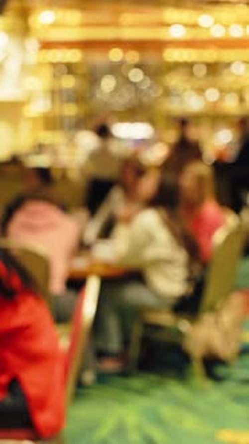 A Blurry Casino Background Image Featuring People Deeply Engaged in Various Exciting Games and
