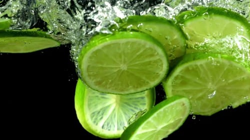 Lime Slices Falling Into Water, Bubbles Forming