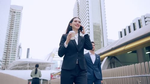 Caucasian young businesswoman talking on smartphone while walk in city.