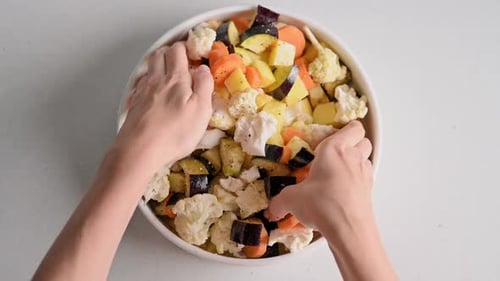 Die Hände einer jungen Köchin rühren gehacktes frisches Sommer-Biogemüse