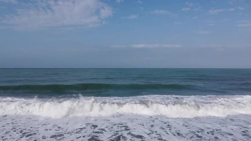Frame split in half: Aerial rises above crisp, blue ocean shore break