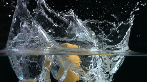 Lemons falling into water in slow motion studio