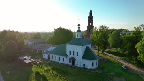 Aerial view of a white church with a green roof and brick tower