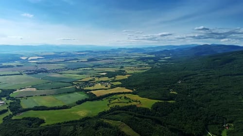 Vast mountain countryside view. Green fields stretch towards distant mountains