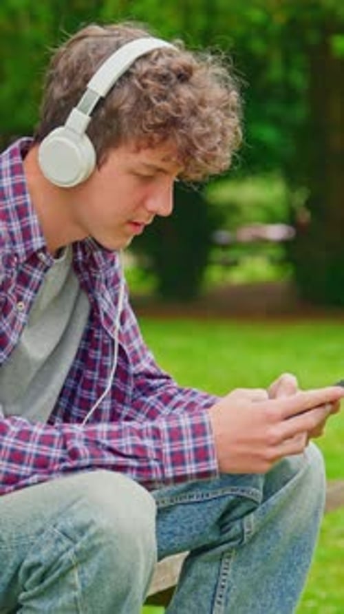 Teenage Boy Listening to Music Outdoors on Phone