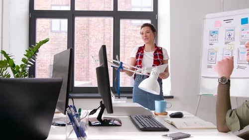 Asian businesswoman presents user interface design to creative team in modern office