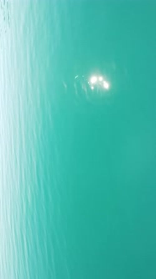 Vertical Aerial View on Sea Water Surface Camera Flies Over Clear Sea Water Sun Glare Abstract