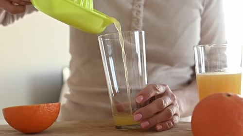 Woman Pours Freshly Squeezed Orange Juice in Glass