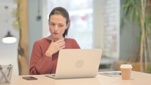 Young Adult Woman Coughing at Desk in Office