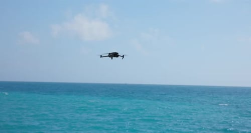 Flying DJI Mavic 3 Pro modern quadcopter drone over sea