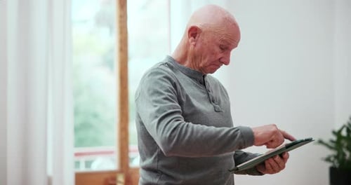 Senior Man Using Tablet in Bright Indoor Setting