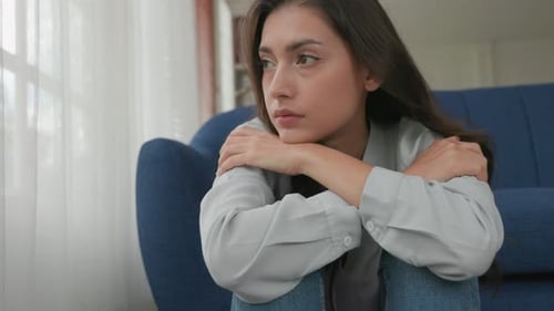 Young Woman Sitting Pensively on Living Room Floor