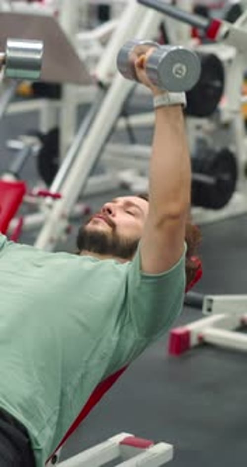 Man Lifts Dumbbells on Weight Bench in Gym