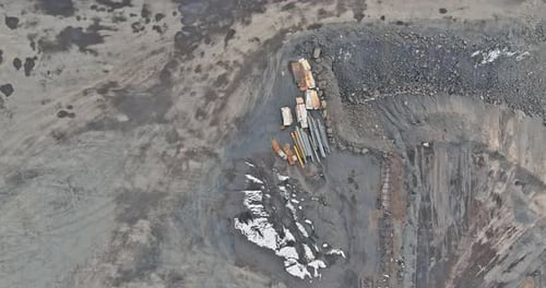 An Excavator at Work in the Quarry Loading Stones Into a Dump Truck During the Mining of Gravel