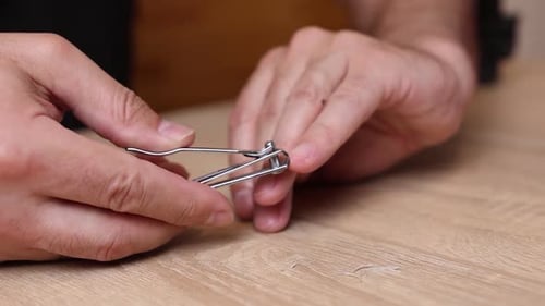 01 1A person trims his nails with nail clippers and polishes the burrs with a file. Personal hygiene