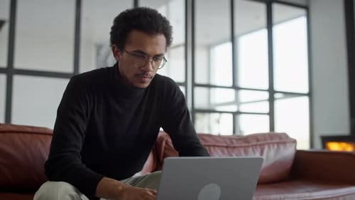 Man Thinking While Working on Laptop at Home