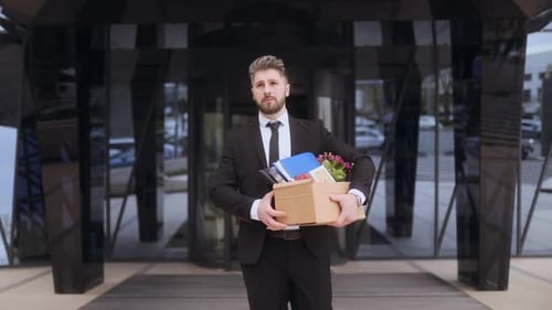 Worker Experiences Layoffs While Carrying Personal Items Outside Office Building
