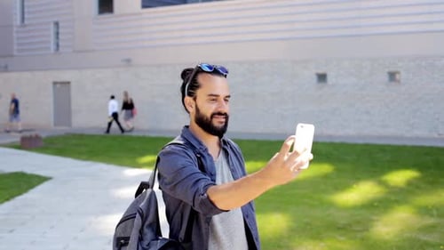 Man with beard smiling and using smartphone
