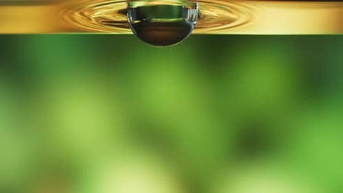 Pure, virgin olive oil with a large drop dipping