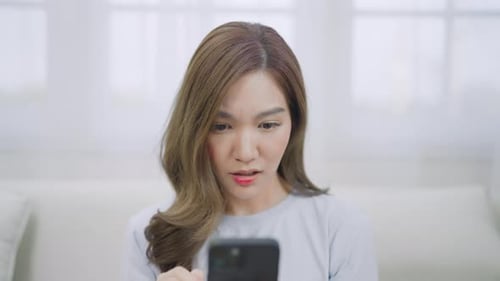 Concerned Woman Viewing Smartphone in Bright Home Interior