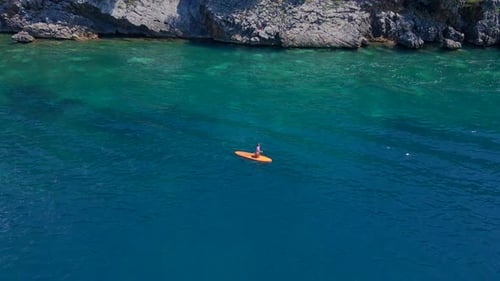 Young Woman on a Stand Up Paddle Board SUP Rawing Among Beatyful Rocks