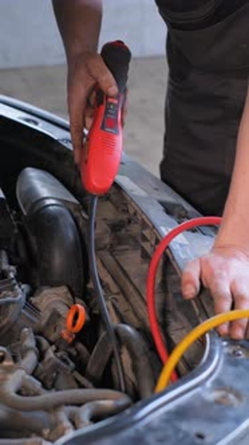 Mechanic Repairing Car's Engine Using Tester