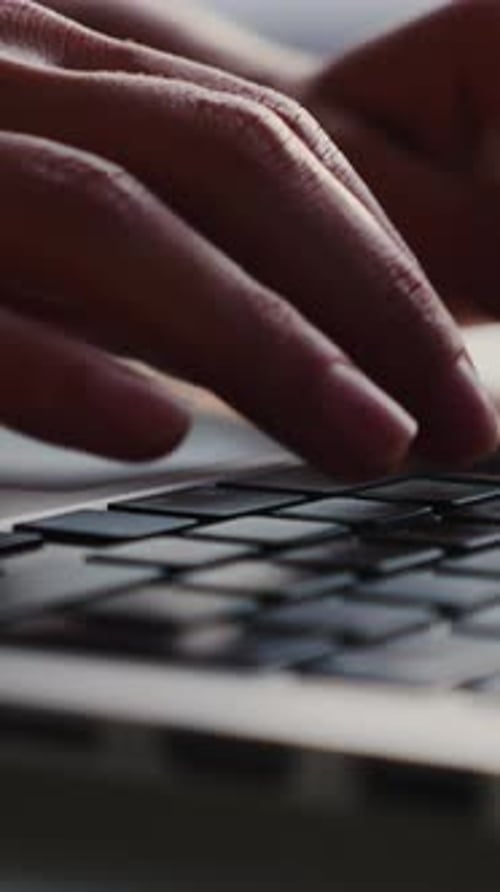 Close up of female fingers using laptop and typing on keyboard. Vertical video