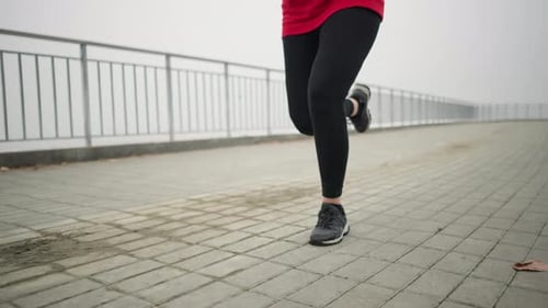 Leg View of Sports Person Jogging in Black Sneakers and Leggings on Outdoor Pathway