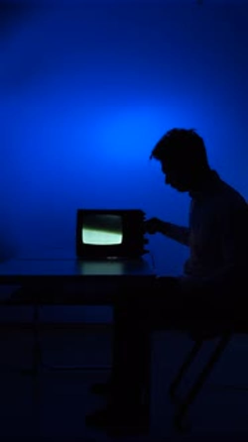 Silhouette vidéo verticale d'un homme réglant un signal sur une télévision rétro vintage changeant de chaîne
