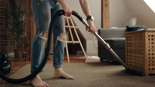 Young Adult Vacuuming Rug in Bright Living Room