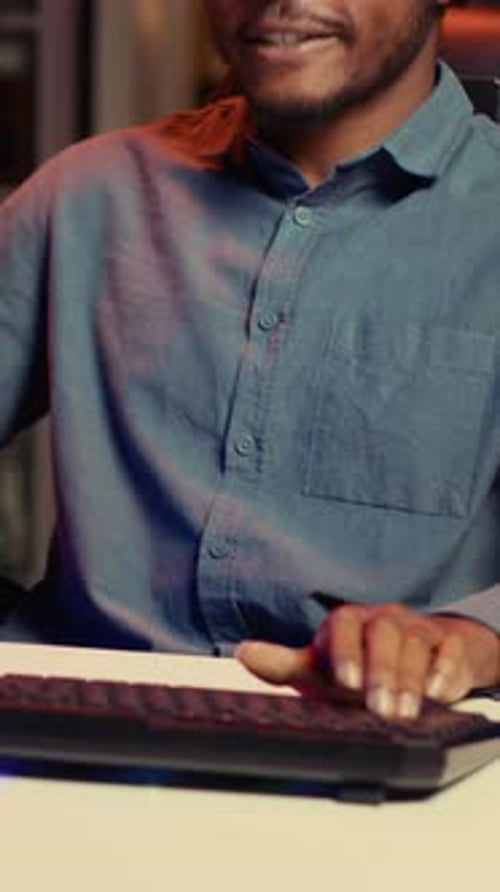 Vídeo vertical: Hombre feliz que usa el teclado de juegos para jugar videojuegos en casa