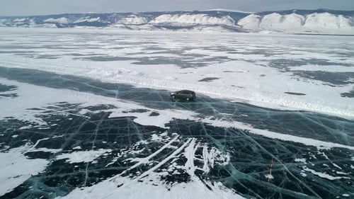 Aerial View on a Car Driving on an Ice Road on Frozen Baikal Winter Landscape of Lake Baikal Drone