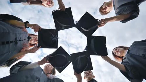 Graduates in Black Robes Join Their Caps in a Circle