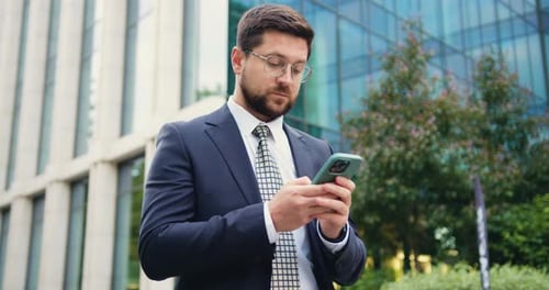 Professional Man in Suit Using Phone Near Office